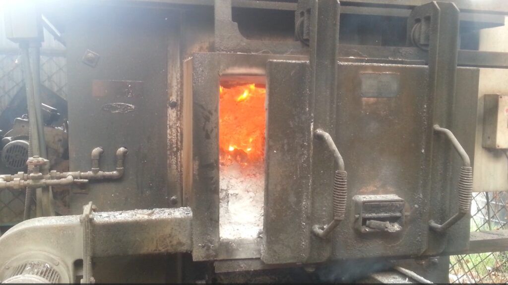 A hospital incinerator burns waste at high temperatures within a heavy-duty combustion chamber