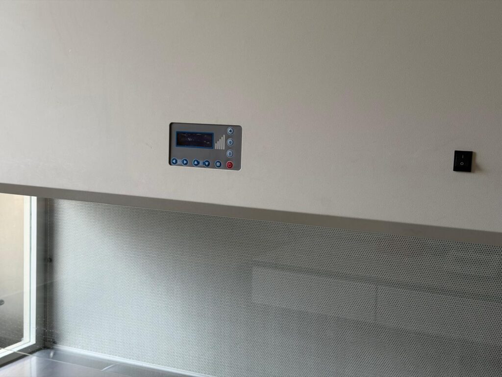 Laminar Air Flow (LAF)Hood or Cabinet with A sleek control panel and power switch mounted on a white wall above a textured gray backsplash
