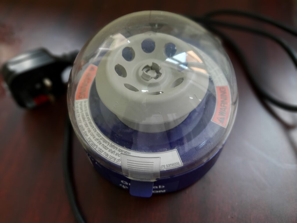 This image shows a compact benchtop mini-centrifuge with a clear dome lid, designed for quick spin-downs of laboratory microtubes.